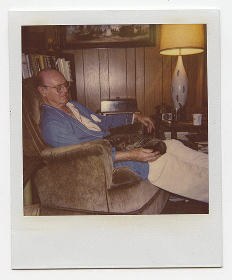 Polaroid of a man in a reclining chair with a cat in his lap