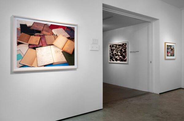 A photograph showing the interior of a white-walled art gallery. Photographs are hung on the walls of the gallery.