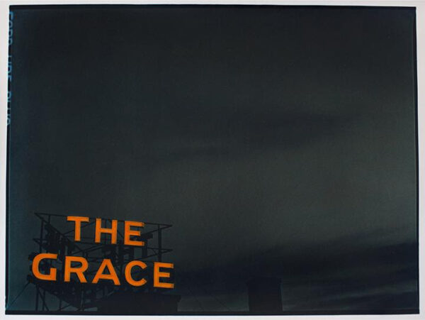 A large-scale photograph of a dark sky. In the lower left corner of the image a red neon sign reads, "The Grace."