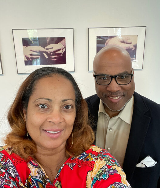 A photograph of Tina and Alfred Walker standing in front of framed works by Richard Prince in a gallery.