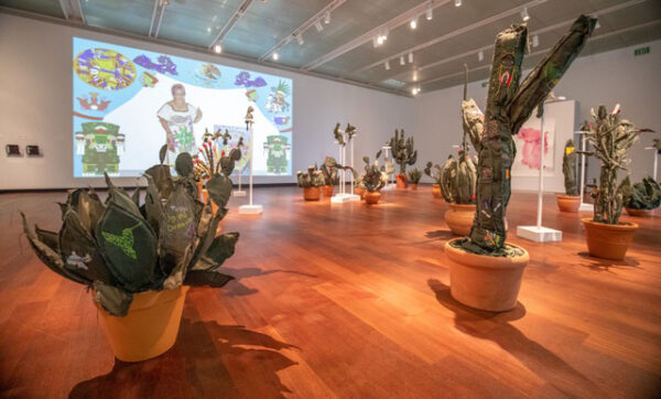 Installation view with fabric cactus sculptures and a large projection