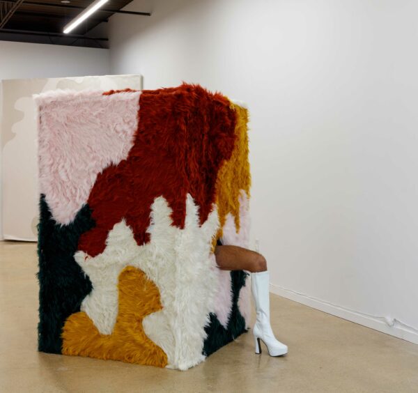 Installation of a box covered in multi-colored fur with a leg sticking out