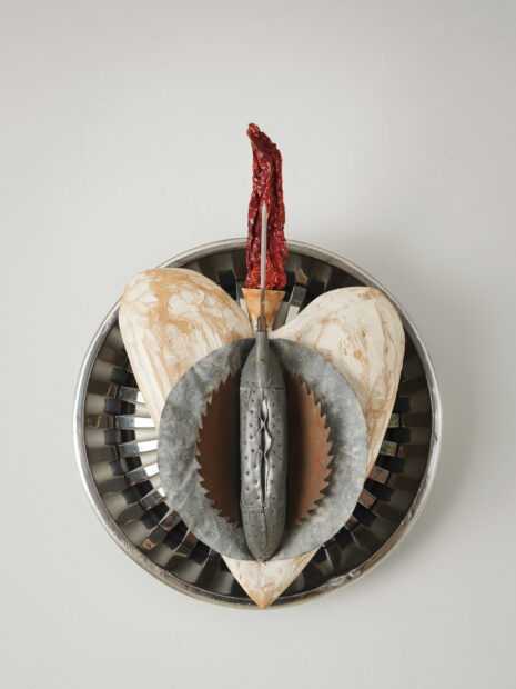 Sculpture of a platter made of a hubcap with a heart and saw on top