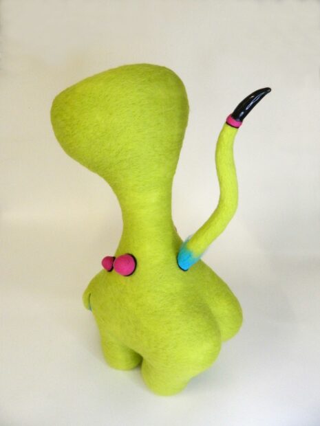 Yellow felt soft sculpture in the shape of a trumpet with a tail