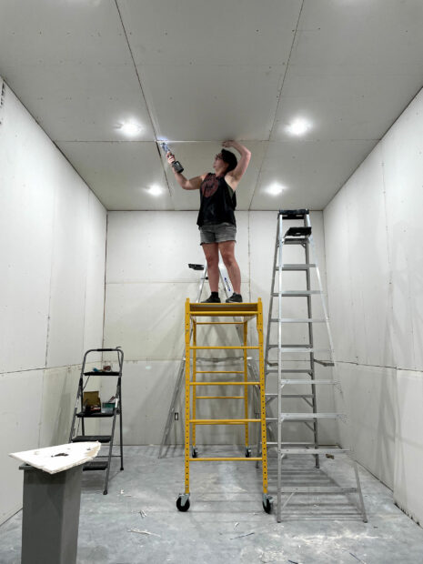 The artist on a a scaffold working on a studio buildout