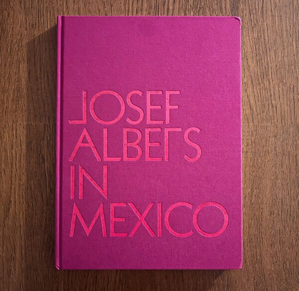 A photograph of the front cover of the book "Josef Albers in Mexico." The bright pink cover features block lettering that spell out the title.