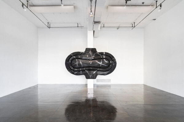 A large sculptural work by K8 Hardy which resembles a feminine hygiene pad painted black.
