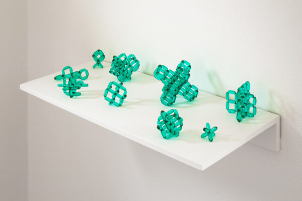 Small green sculptures on a white shelf