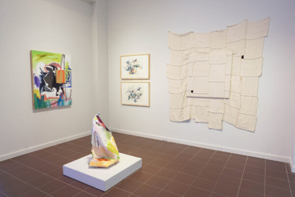 Installation view of various mixed media works on a wall and a sculpture on a plinth