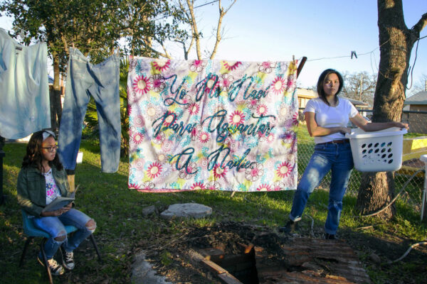 Photo of two women next to a sheet hanging on a clothesline