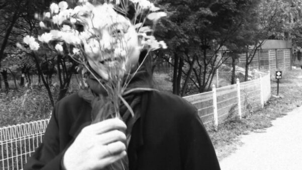 Black and white image of a woman hiding behind flowers