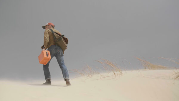 Image of an artist walking through a sand storm