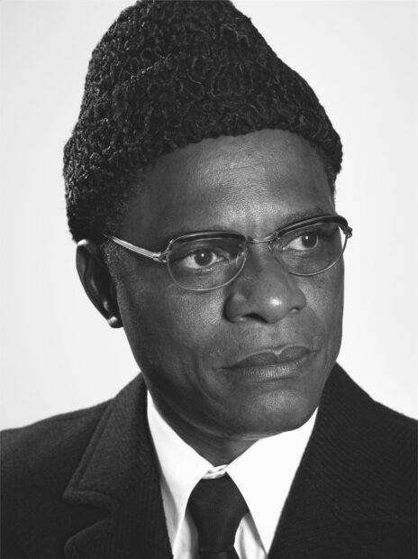 A black and white photograph of Samuel Fosso posing as French poet Aimé Césaire.