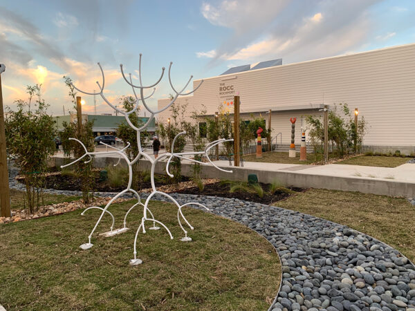 A photograph of the Rockport Center for the Arts sculpture garden. A large-scale white sculpture by James Surls sits in the foreground.