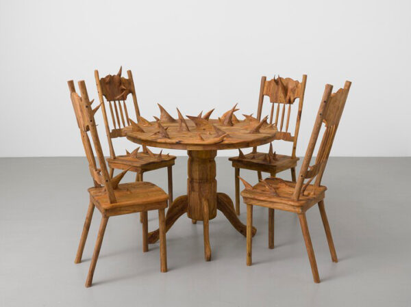 A wooden sculpture by Hugh Hayden of a table and chairs with spikes poking out.