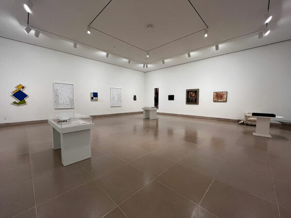 An installation image of several paintings hanging on a white gallery wall.