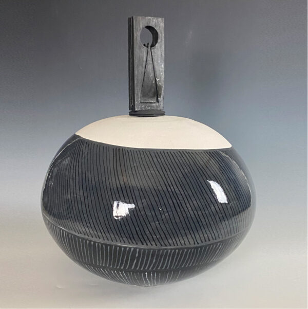 A ceramic sculpture featuring a large, round, black and white base, with a rectangular shape on top.