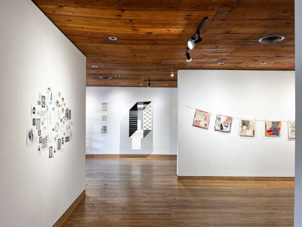 A photograph of an exhibition featuring small and medium sized works displayed on white gallery walls.