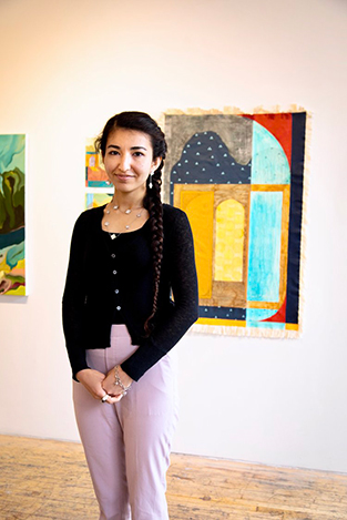 A photograph of the artist Farangiz Yusupova standing in front of her work.