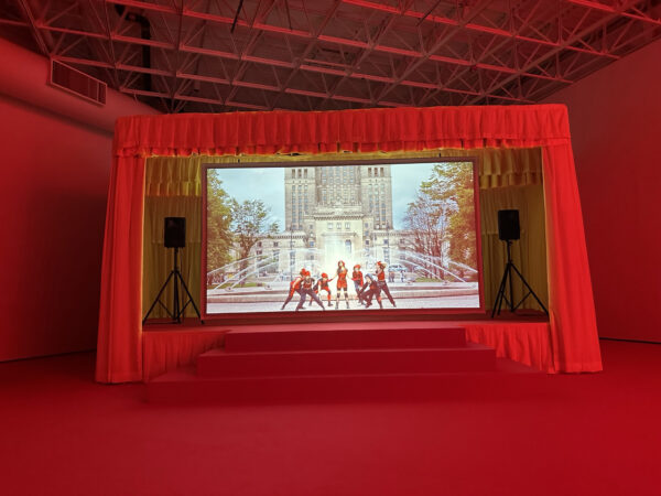 Red theater room with a video projection of KPop dancers