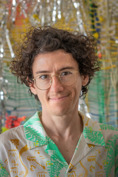A headshot of Ian Gerson in front of a textile work.