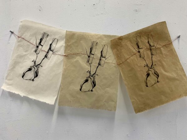 Photo of works on paper of hearts suspended by clothespins on a clothing line