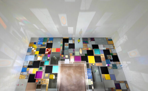 A photograph of a large-scale installation on a wall filled with bright and reflective surfaces.