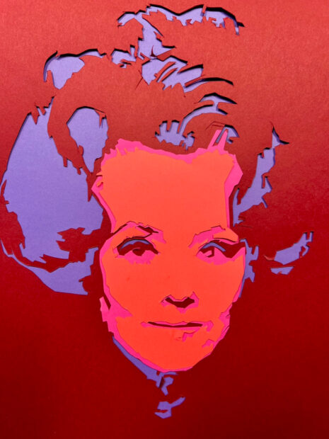 A woman's face, made up of cut paper. The woman has a large hairstyle.