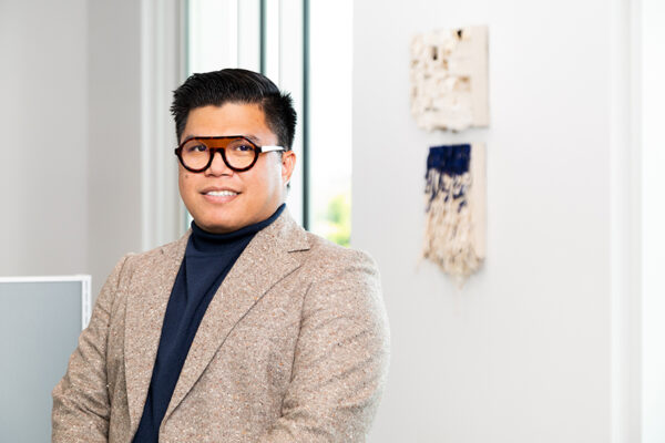 A headshot of Matt Manalo in front of two small works by the artist.
