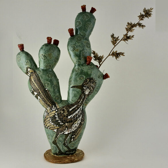 A clay work by Lynn Armstrong of a roadrunner set against a prickly pear cactus.
