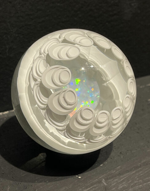 A round sculpture with a glittering marble inside