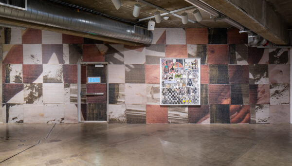 Installation of a quilt-like mural on a wall with a two dimensional work on top