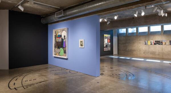 Installation view of two dimensional works on black, blue, and concrete walls