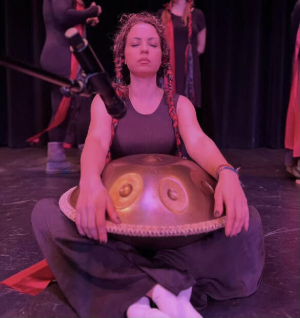 A woman sitting on the floor playing the handpan