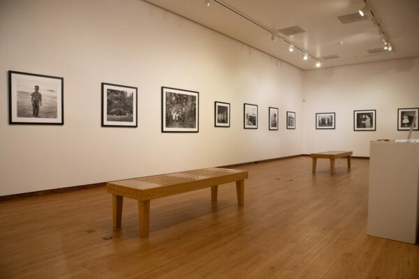 An installation image of black and white photographs hanging in a gallery.