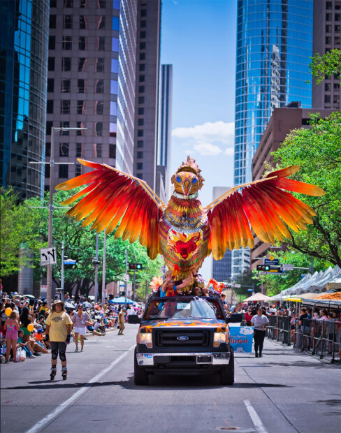 A photograph of a truck carrying a tall sculpture of a phoenix. 
