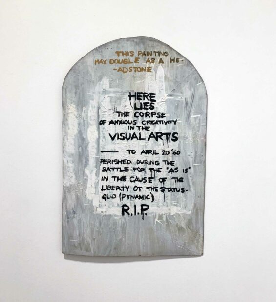 An artwork that features writing on a curved, headstone-shaped obejct.