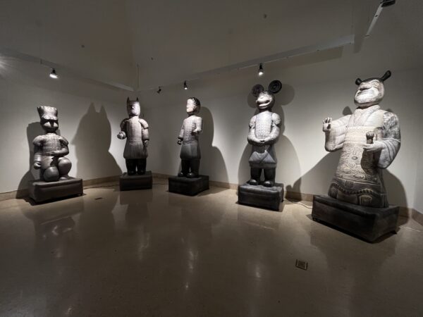 A installation image of five large inflatable sculptures of warrior-like figures with heads of cartoon figures including Bart Simpson, Batman, Spiderman, Mickey Mouse, and Shrek. Artwork by Lizabeth Rossof.