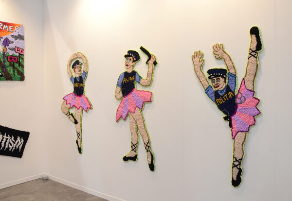In this wall sculpture, police officer-looking figures wear tutus and are in ballet poses.