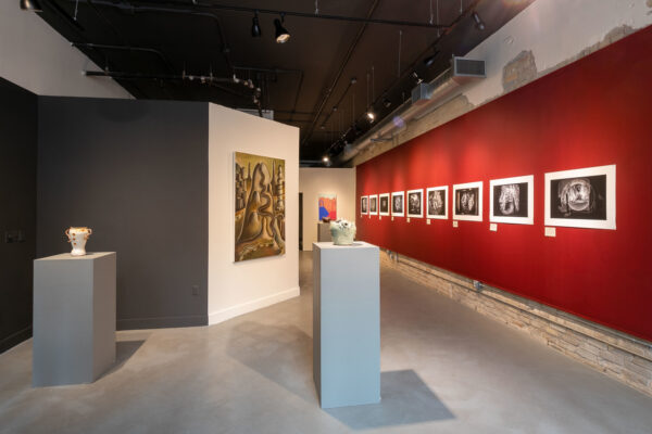 Installation view of work on walls and pedestals in a long, narrow space