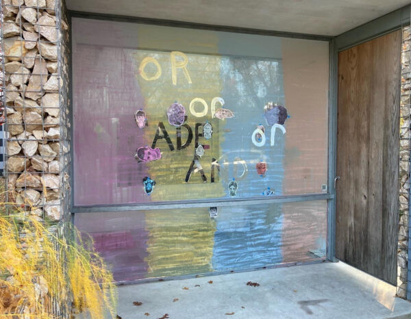 A window is covered in words and objects. The words are "or," and the objects are multicolored.