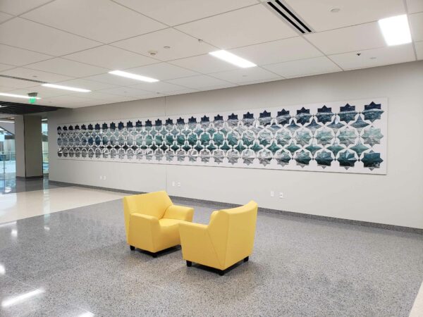Installation image of a long, horizontal piece with blue, white and green tesselations