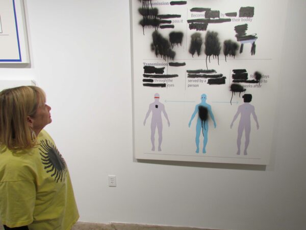 Photo of a woman in a green tshirt in front of a work on paper