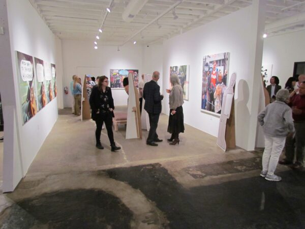 Visitors in an exhibition space with large two dimensional works on a white wall