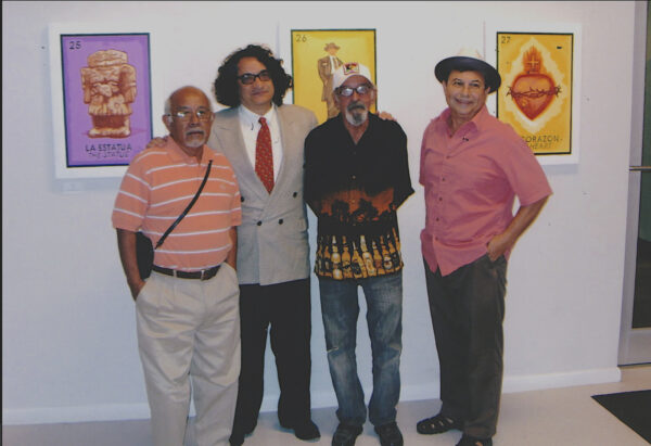Photo of four men standing in front of three paintings