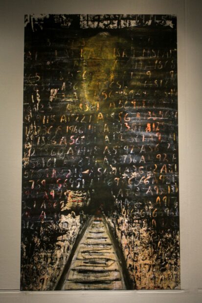 dark painting on canvas with train tracks in the center and numbers and letters written into the black backdrop