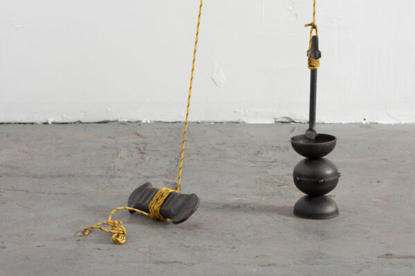 A photograph of small steel pieces with rope tied around them as part of an installation by Cara Rae Joven.