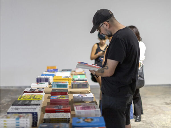 A photograph of a small group of people looking at books set out on tables. 