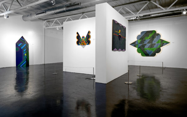 Two dimensional works on white walls and a sculptural piece standing freely against the wall