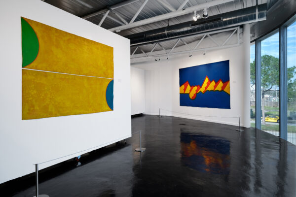 Two large horizontally oriented paintings on a wall, on the right a yellow one, on the left a blue one